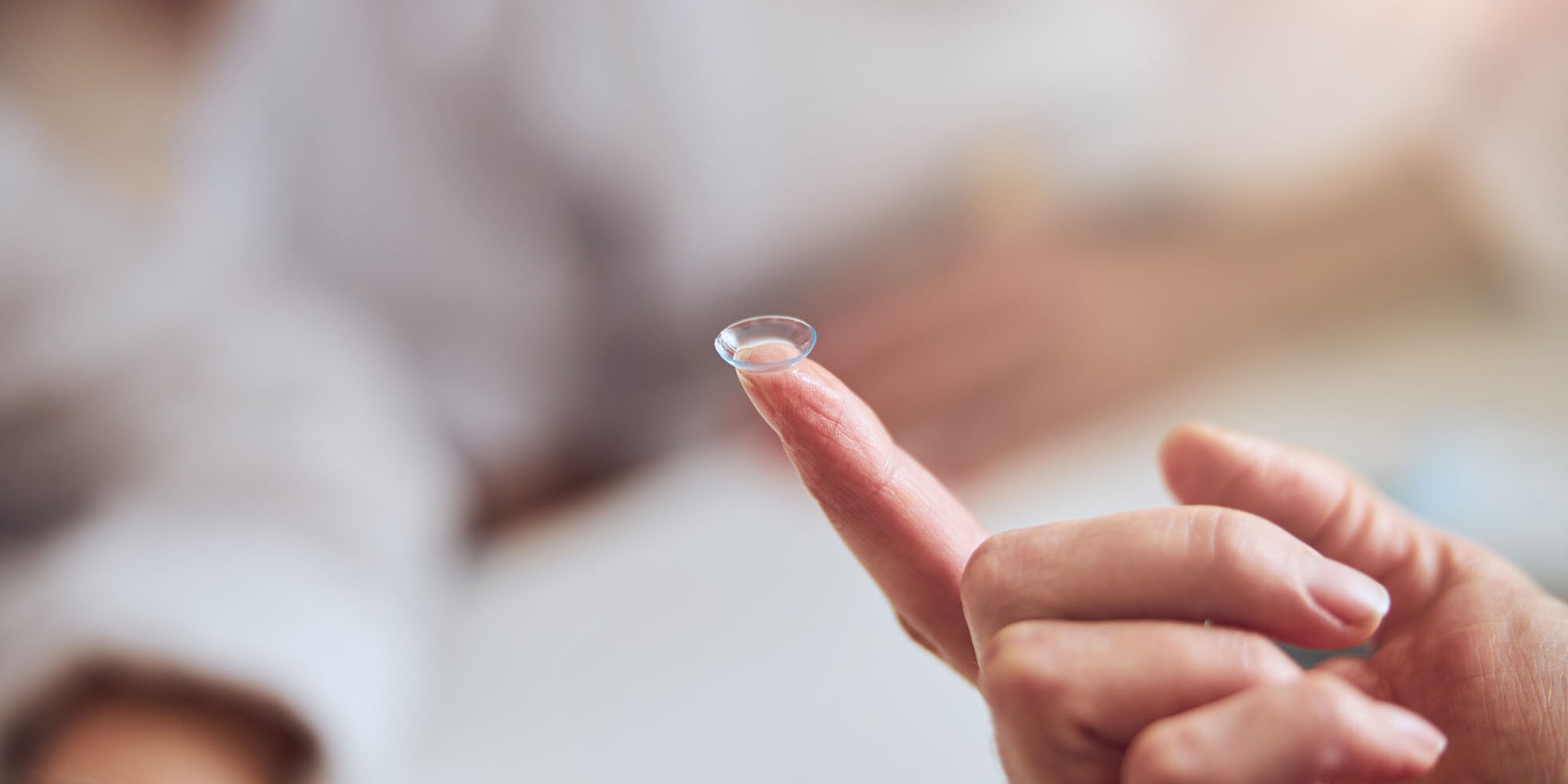 Focused image of professional lens for eye vision Close up portrait of female arm with eye lens on finger isolated on white background