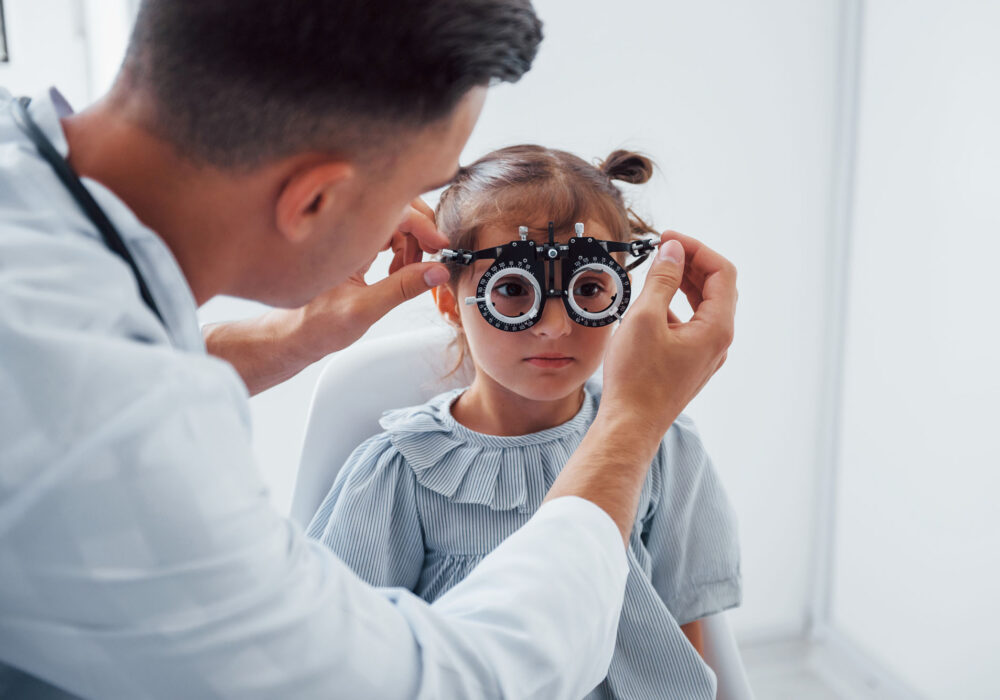 Testing vision. Young ophthalmologist is with little female visitor in the clinic Testing vision. Young ophthalmologist is with little female visitor in the clinic.