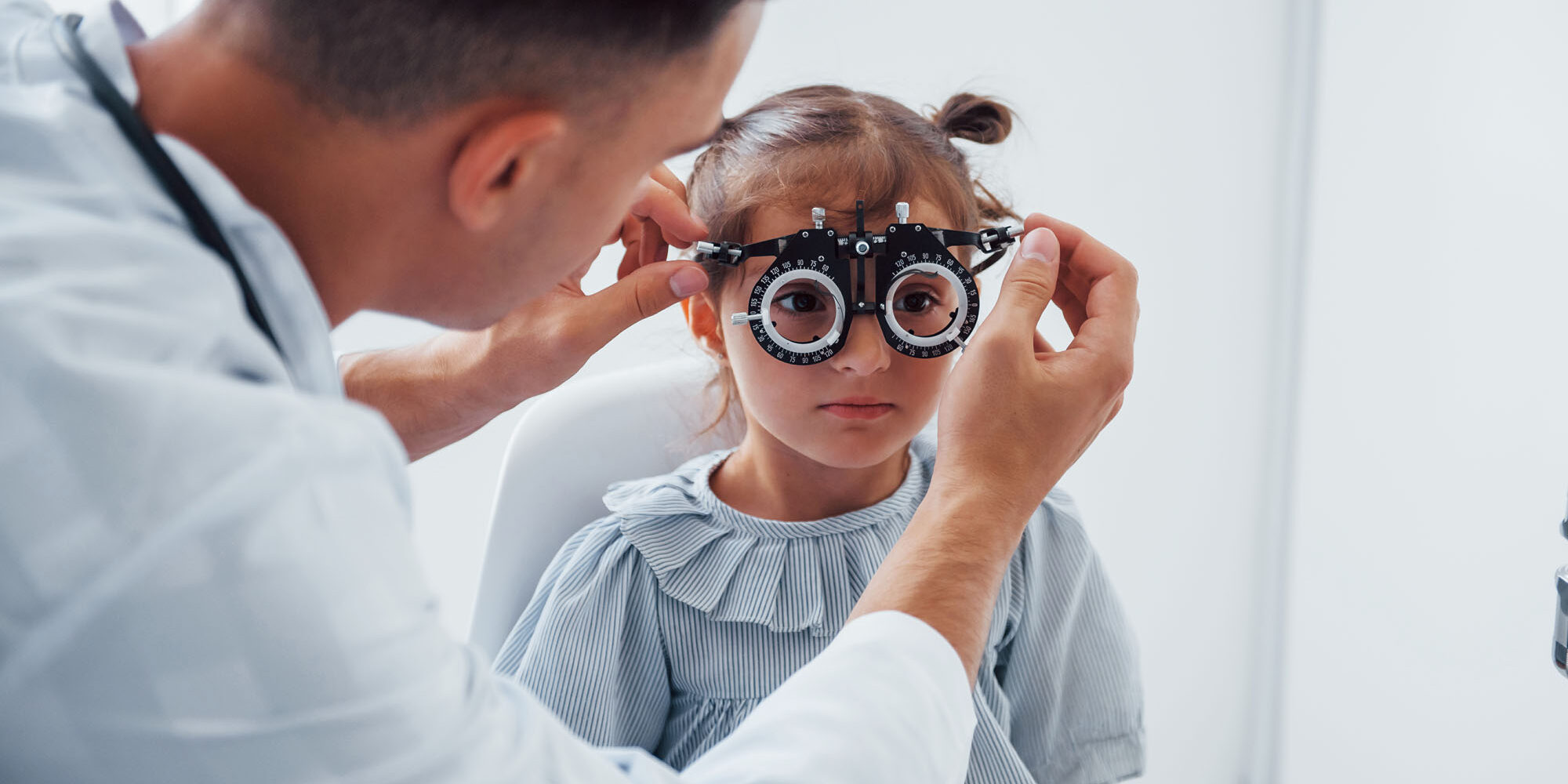 Testing vision. Young ophthalmologist is with little female visitor in the clinic Testing vision. Young ophthalmologist is with little female visitor in the clinic.